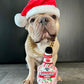 Dog wearing a Santa hat with a bottle of peppermint schnapps.