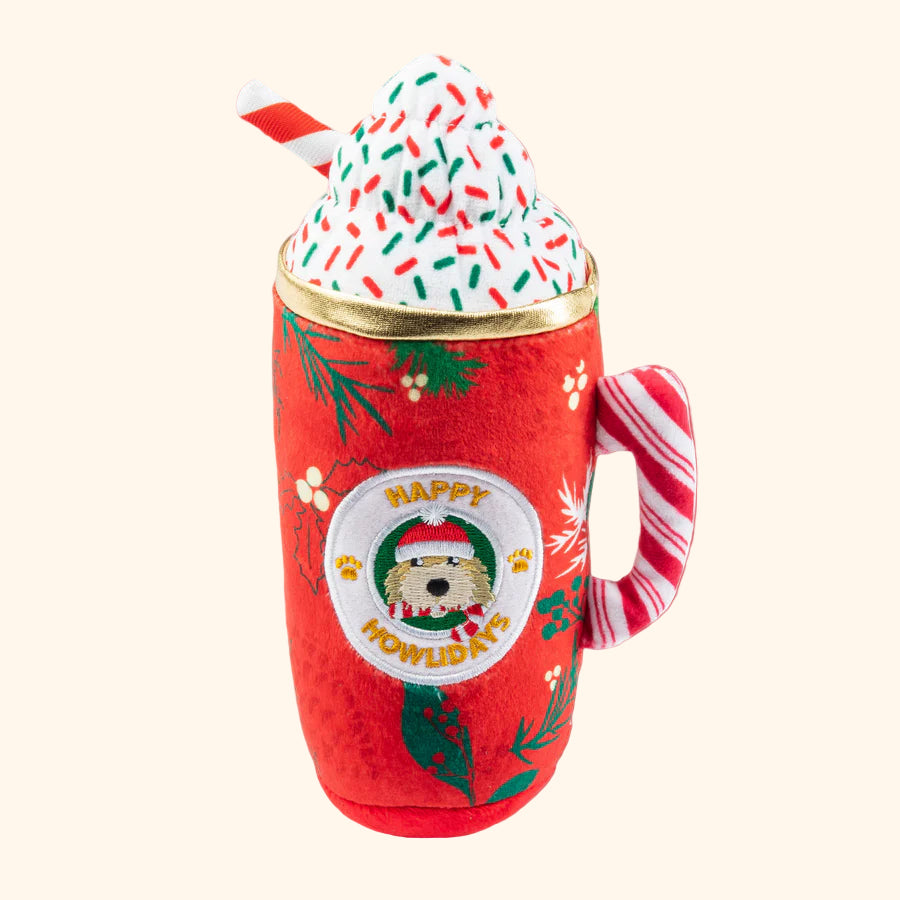 Red mug with Christmas design, filled with a faux hot chocolate and whipped cream, on a white background.